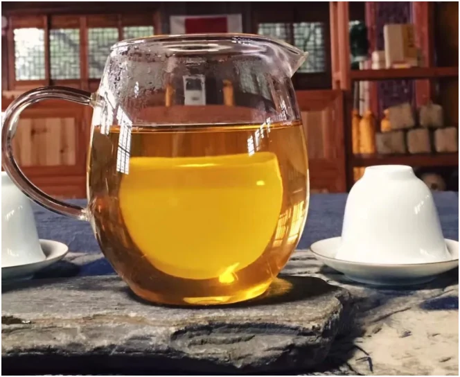 Amber Fu brick tea in a glass pitcher beside bookshelves