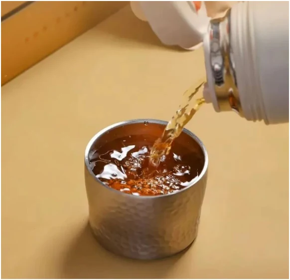 Amber white tea pouring into a small textured cup