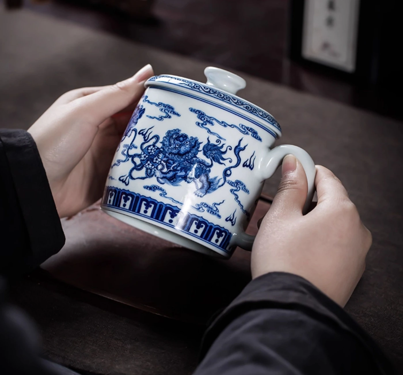 Bouilloire en porcelaine bleue et blanche avec cuit au bois un motif de lion et de brocart : tenue dans les mains