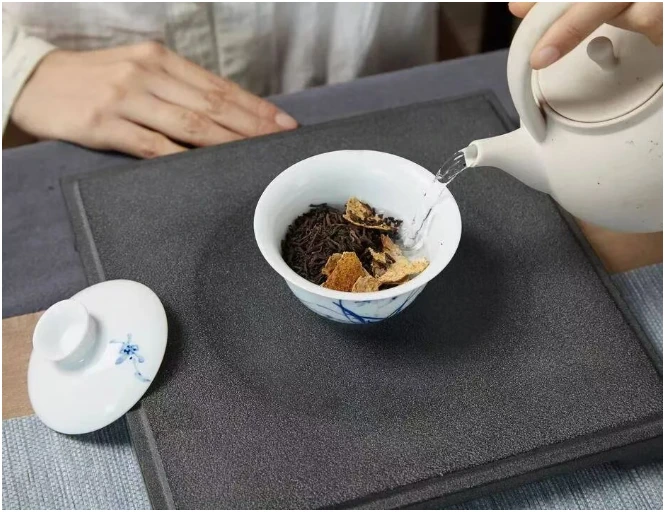 Pouring hot water over citrus peel and tea in a gaiwan