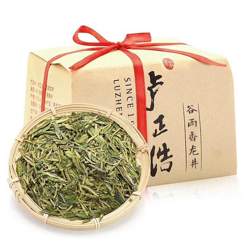 Longjing tea gift packaging beside a basket of dry leaves