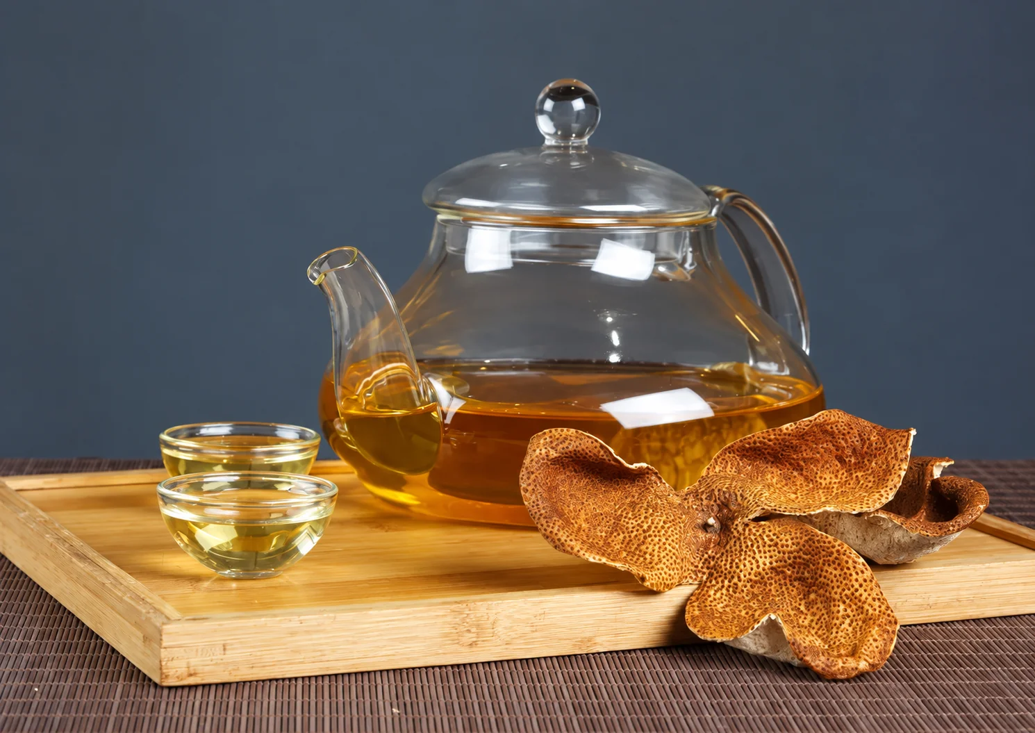 Glass teapot and small cup beside dried peel