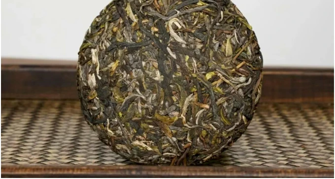A round compressed raw Pu-erh cake on a tea mat