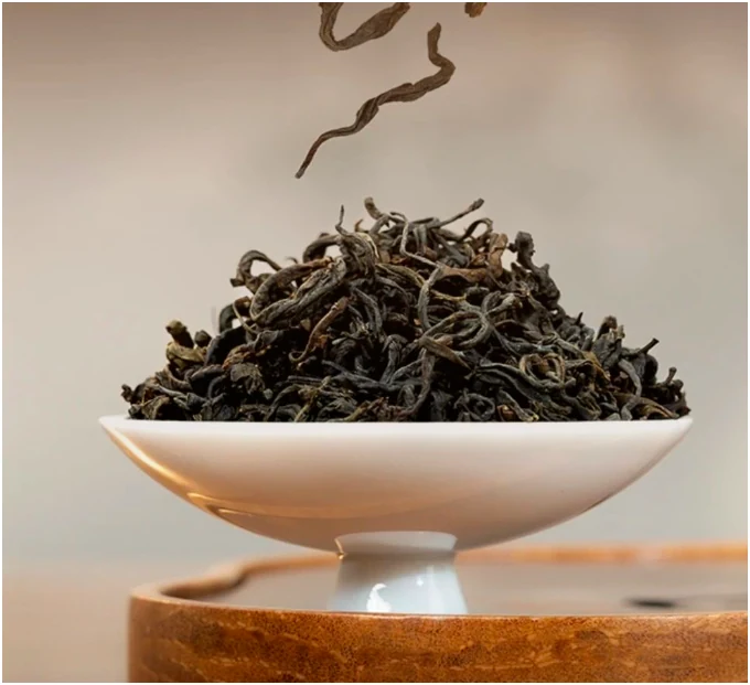 Dry dark tea leaves in a white pedestal dish