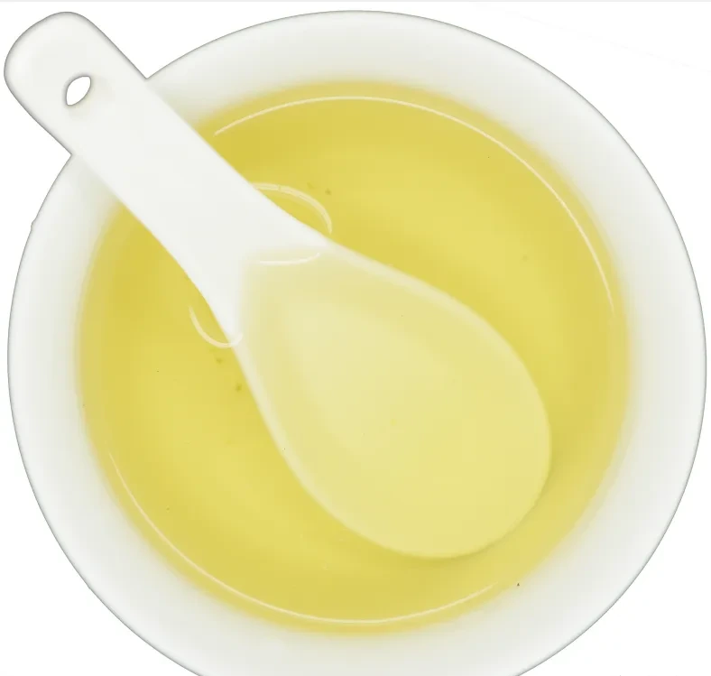 Yellow tea liquor in a white evaluation bowl with a spoon