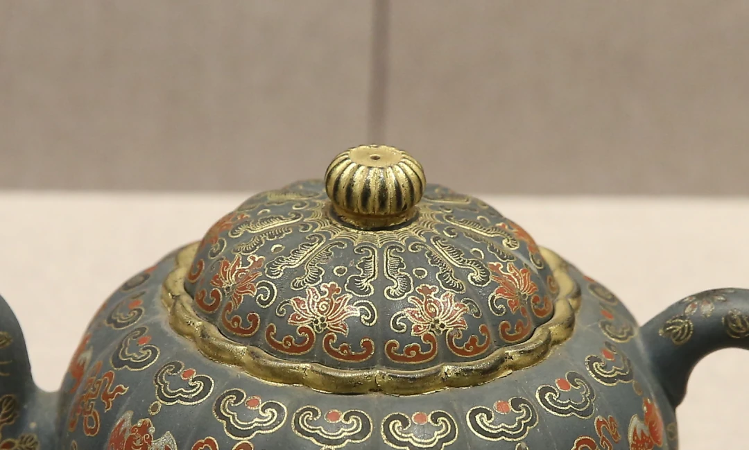Des contours dorés et une décoration florale sur le couvercle d'un Yixing vase de fond vert