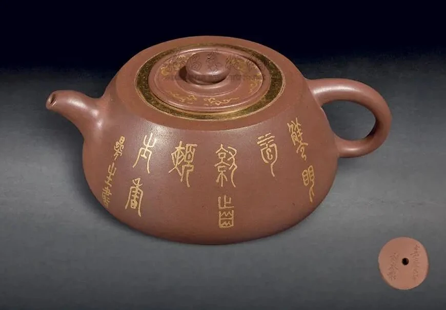 Boîtier petit argile théière avec une inscription en caractères dorés et un couvercle décoré