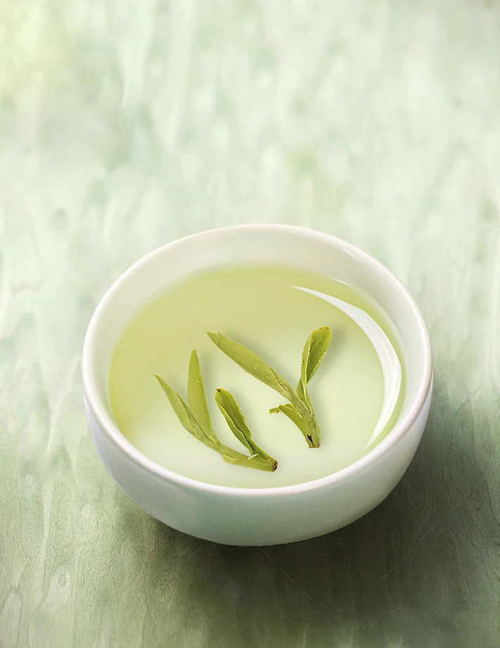 Opened Longjing tea leaves in pale green tea liquor