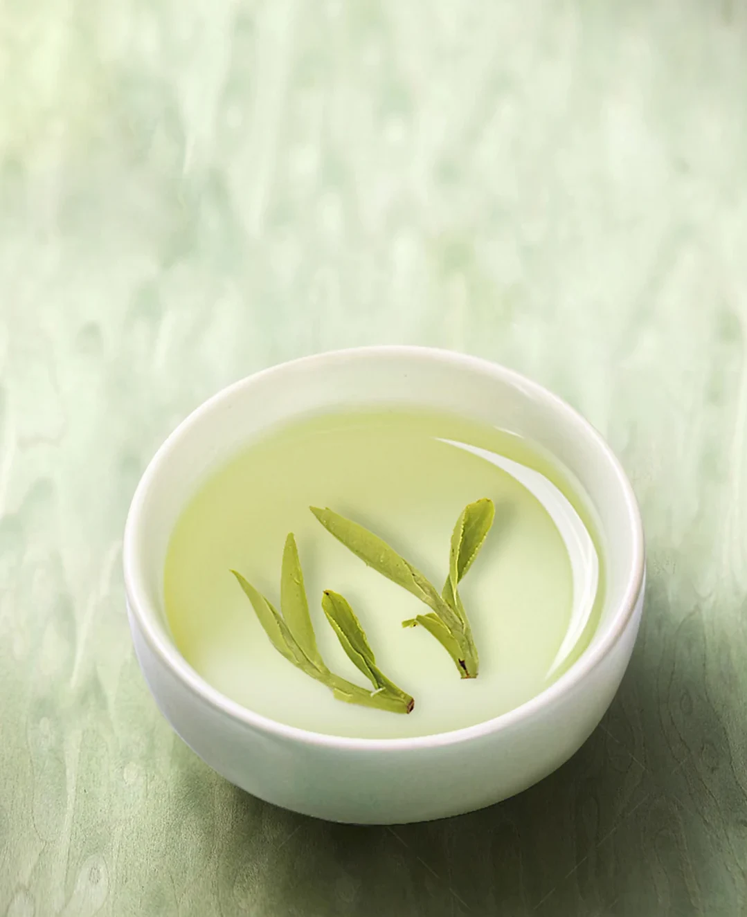 Opened Longjing tea leaves in pale green tea liquor