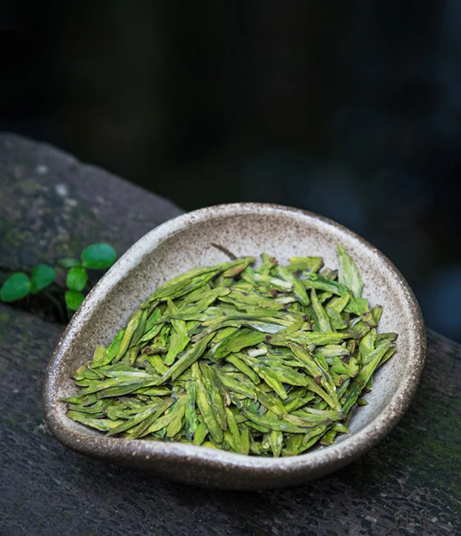 Flat dry leaves of Gong Pai Longjing green tea
