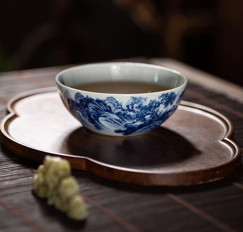 Landscape teacup filled with tea on a wooden tea tray