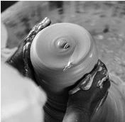 A craftsperson forming a ceramic bowl on a wheel