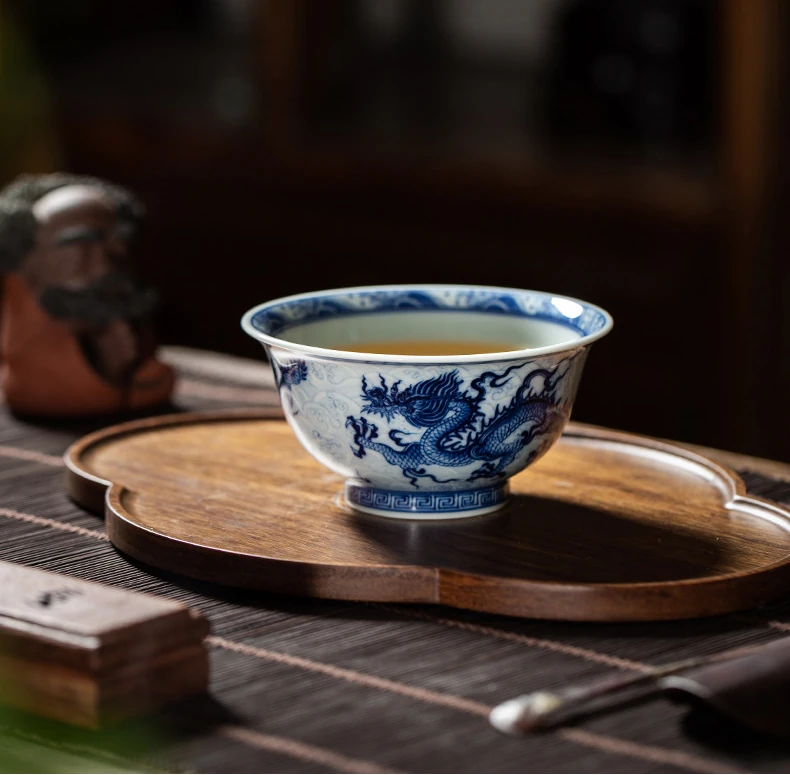 Dragon teacup filled with tea on a wooden tea tray