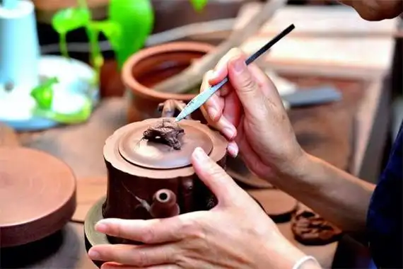 Handwerker bei der Arbeit an einer ton Verzierungsfigur auf einer teekanne Klappe