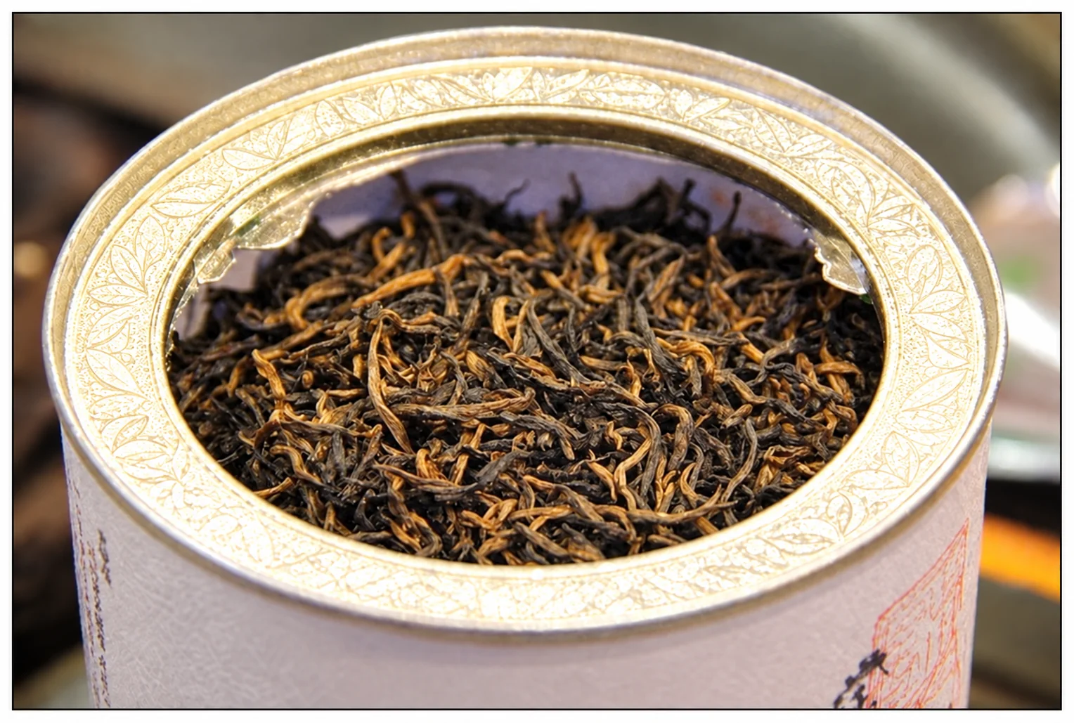 Fine dark and golden tea buds in an open tin