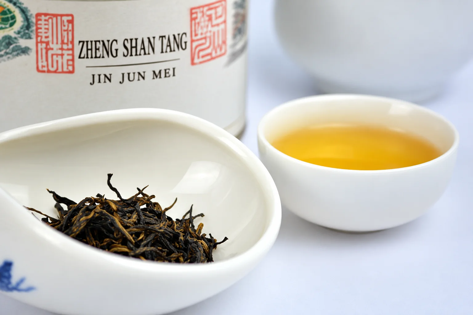 Dry tea sample beside a cup of golden black tea
