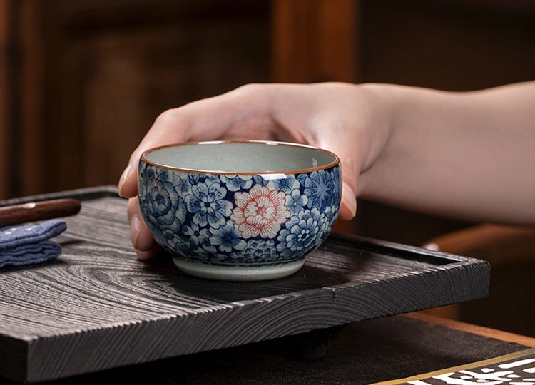 Hand-painted floral teacup resting on a wooden tea tray