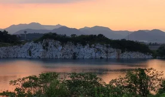 Un lago bajo los pálidos acantilados rocosos y las colinas distantes al atardecer