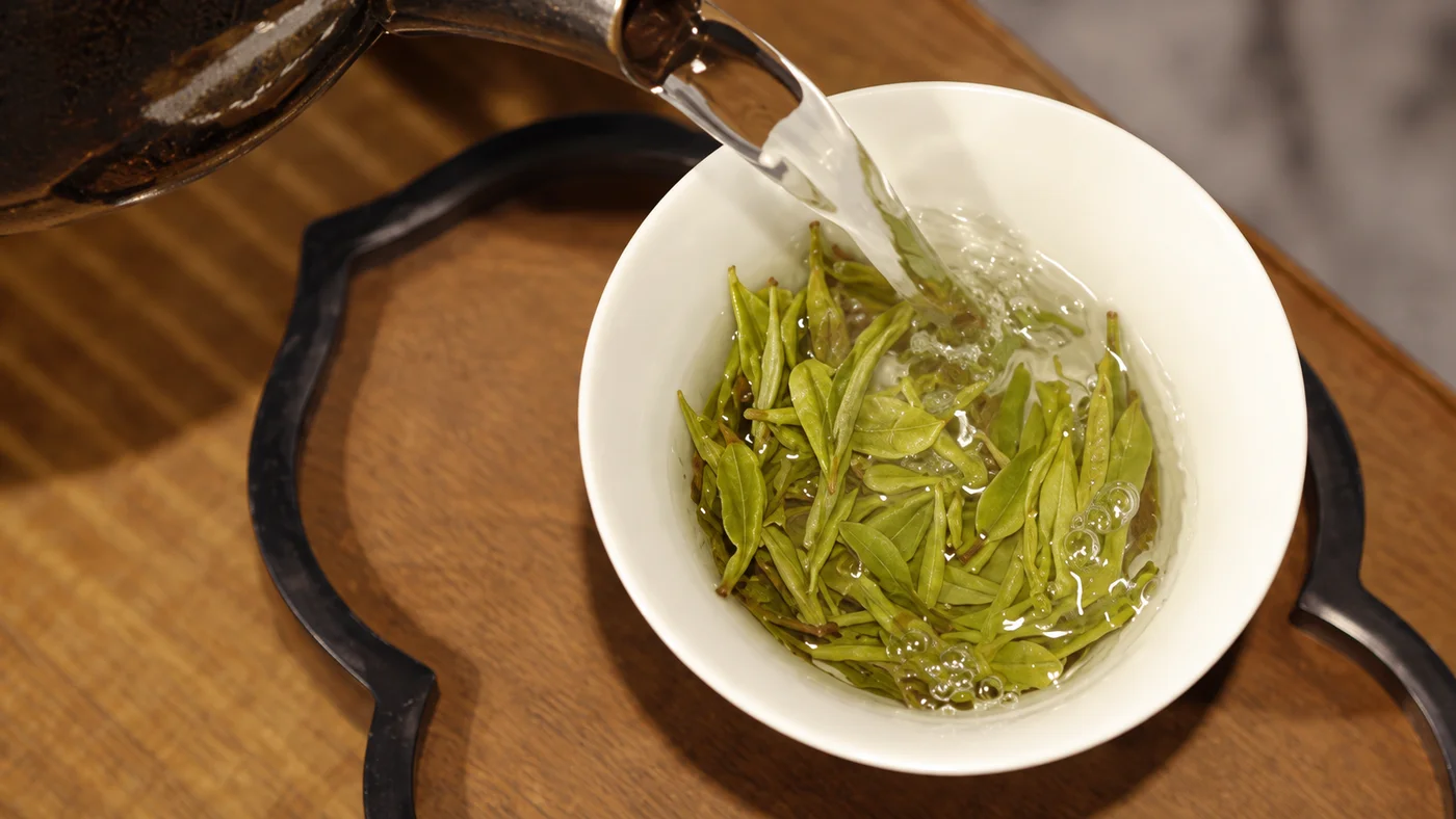Overhead view of tea poured into a white bowl with leaves