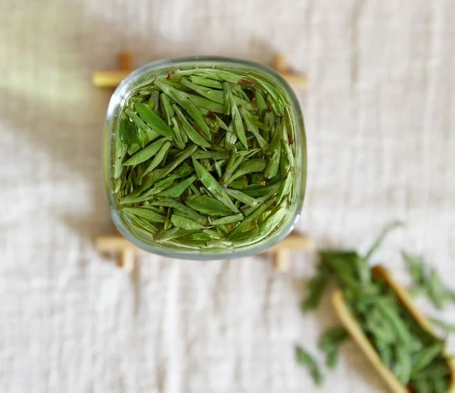 Overhead view of green tea leaves in a glass infusion