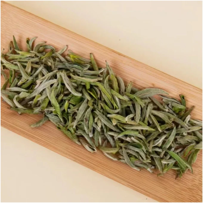 Loose White Peony tea leaves on a wooden scoop