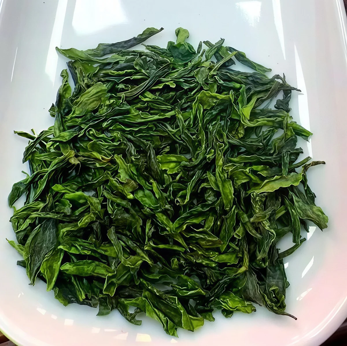 Broad Lu’an Guapian dry leaves on a white plate