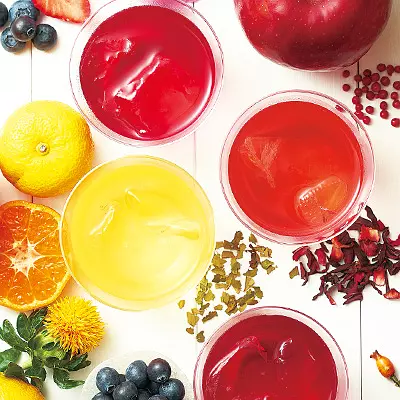 Overhead arrangement of red and yellow iced fruit teas with fruit and flowers