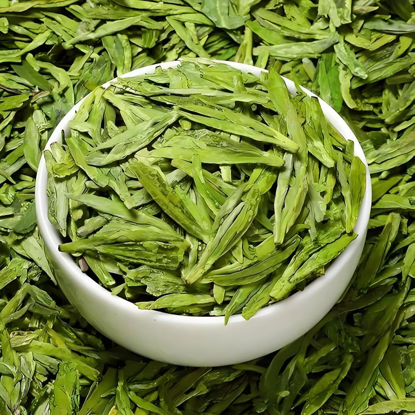Dry Longjing leaves displayed in a bowl among green foliage