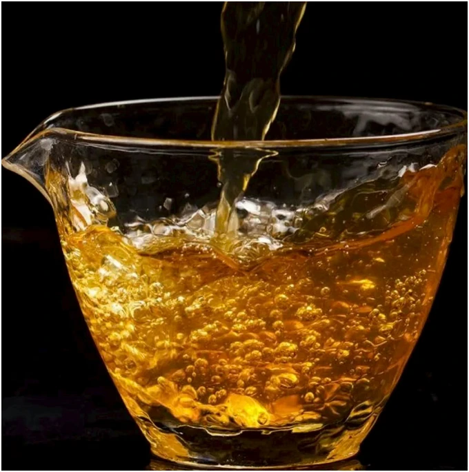 Golden amber tea being poured into a glass vessel