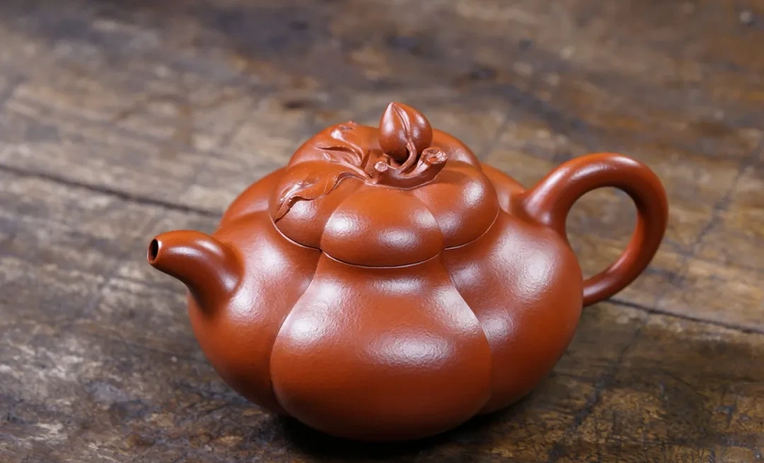 Pumpkin-shaped reddish-brown teapot with a leaf-and-bud lid finial