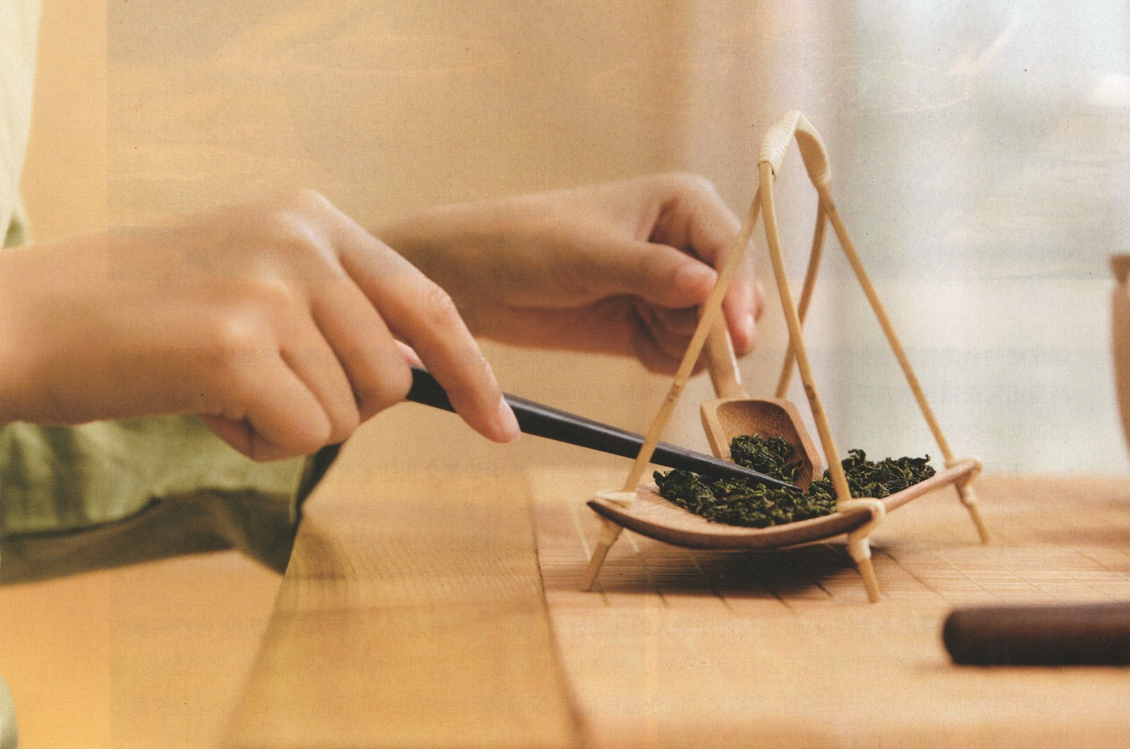 Hands weighing loose-leaf tea with a traditional hanging balance