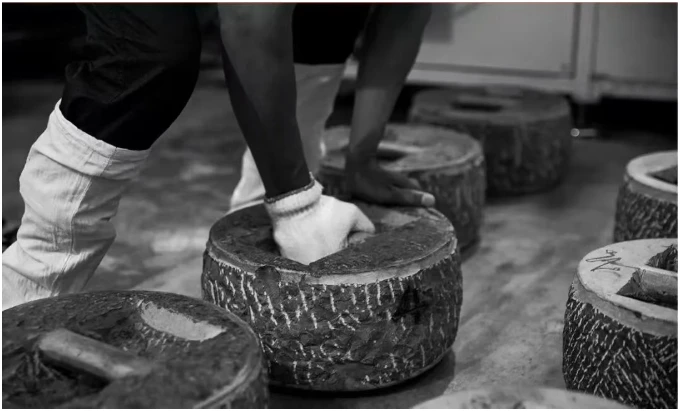 Hands pressing tea with a traditional stone weight