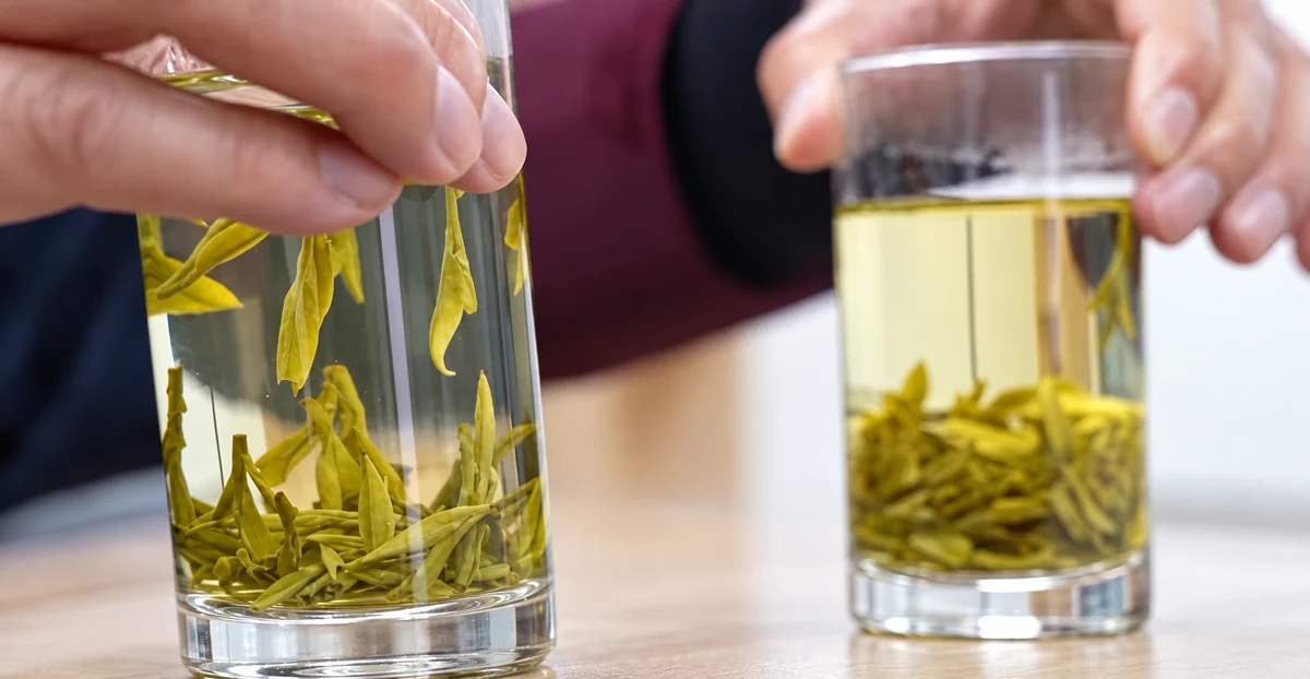 Two glasses of Longjing tea showing leaves and different infusion colors