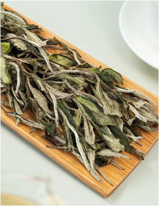 White Peony tea leaves and buds in a narrow bamboo scoop