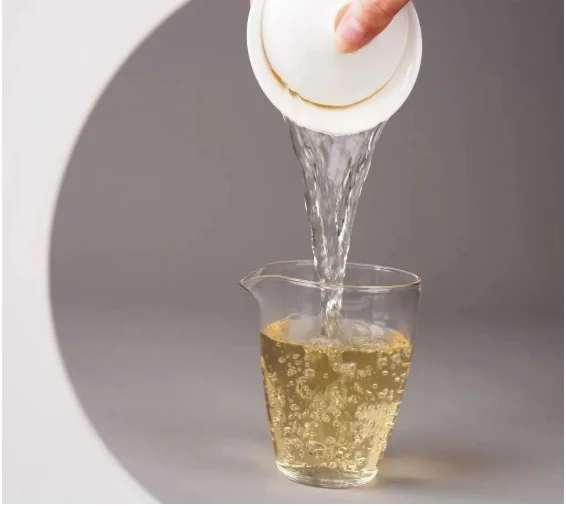 White tea being decanted from a gaiwan into a glass pitcher