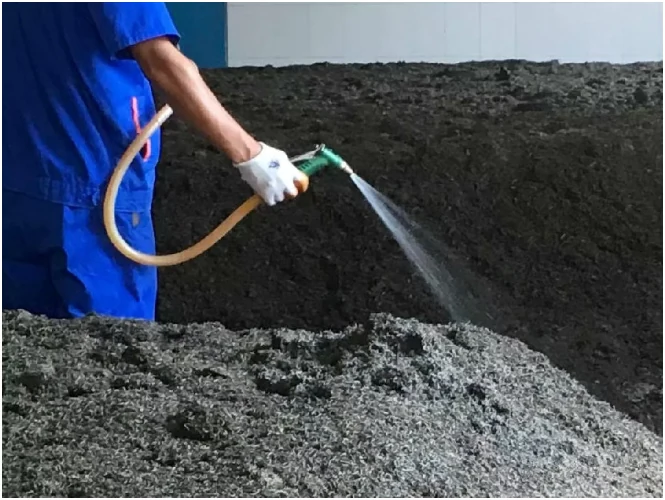 Worker adding water to a tea fermentation pile