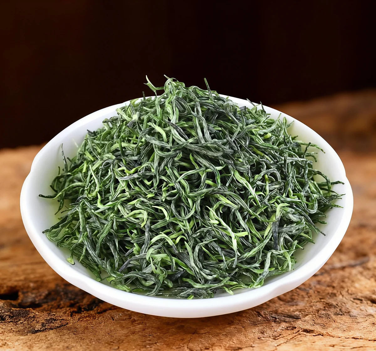 Fine Xinyang Maojian tea leaves piled on a white plate