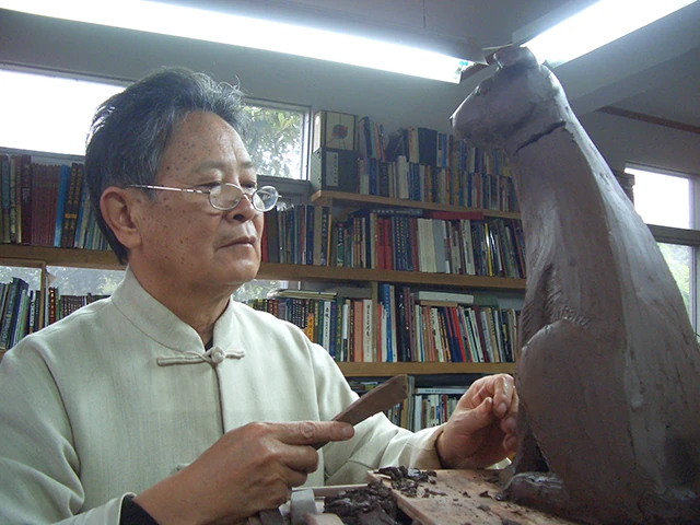 徐希唐が工房で手工具を使って彫 陶土 刻を形作っている。