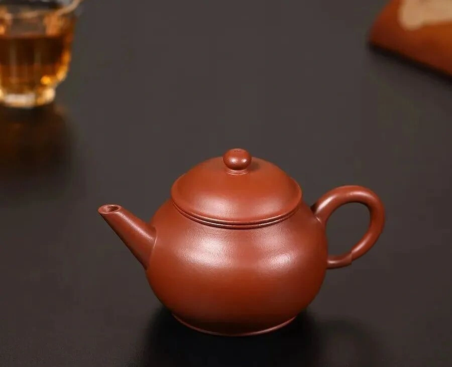Reddish brown Shuiping-shaped teapot with a rounded body and curved handle
