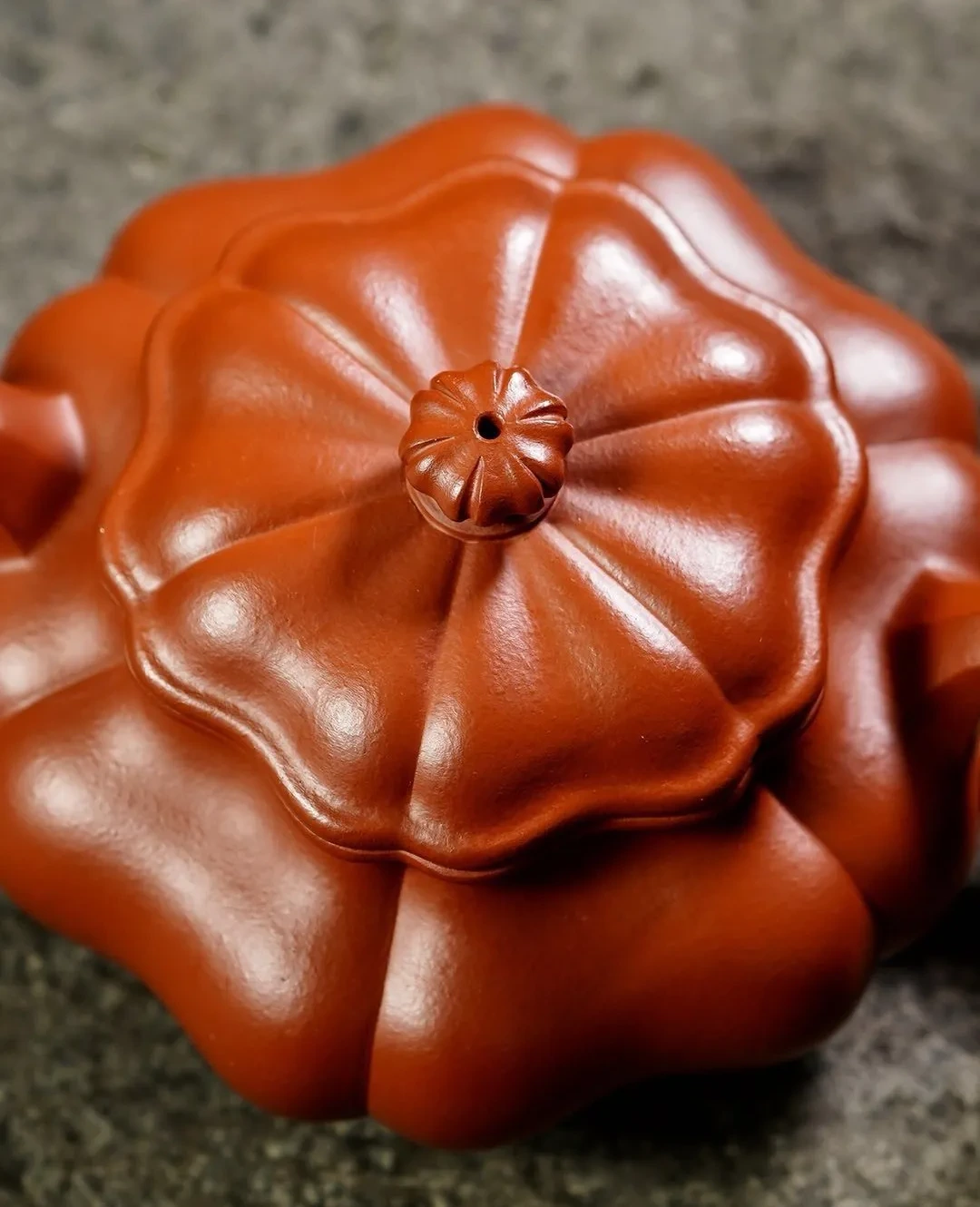 Close view of the ribbed lid and pierced flower-shaped knob of a red clay teapot